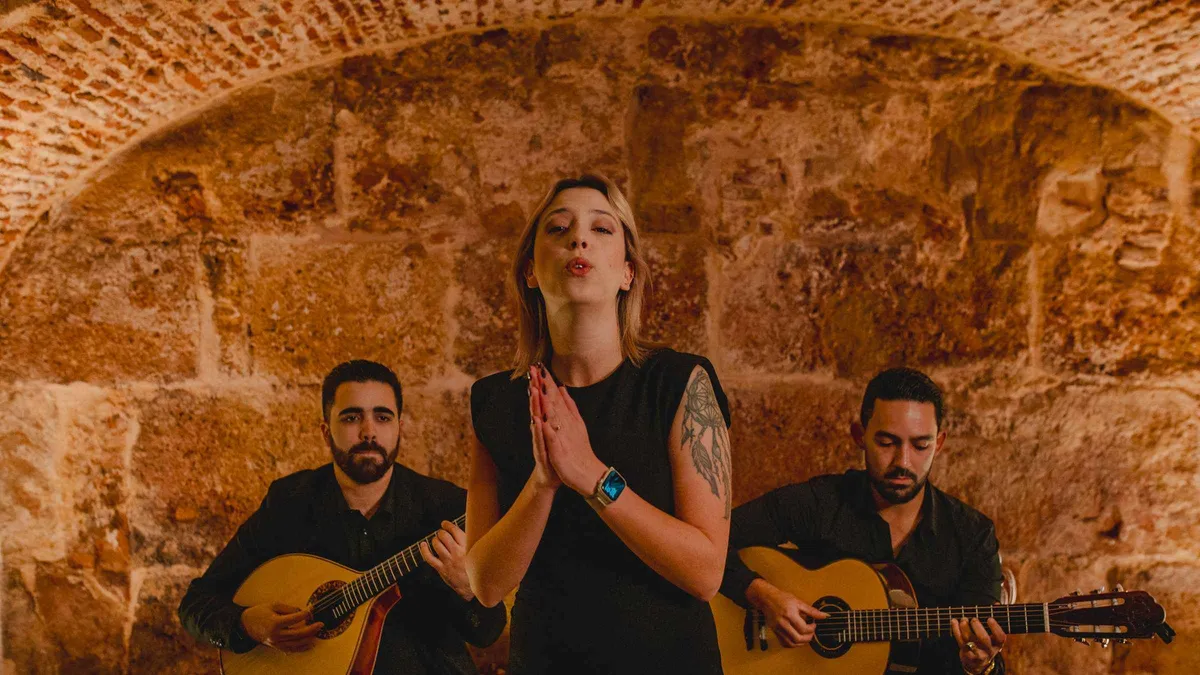 Fado singer with two guitarists performing in a candlelit room at a top-rated authentic Fado show with wine in Lisbon