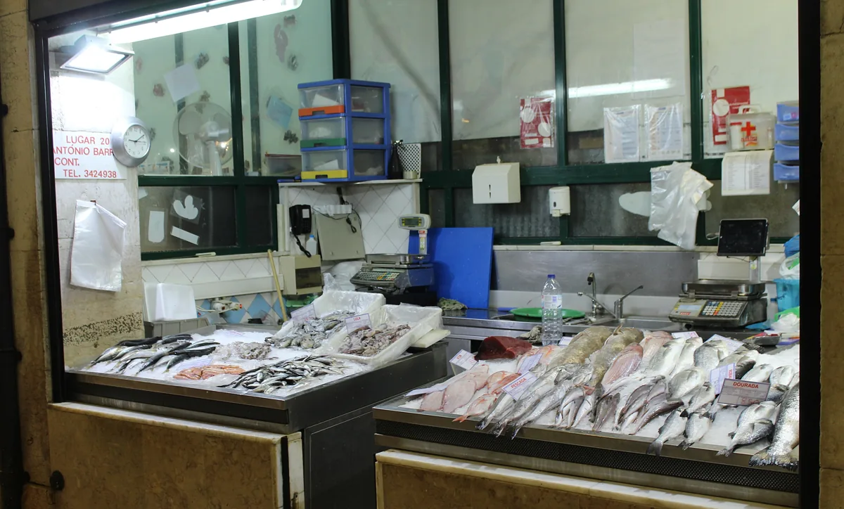 A fish counter at the Mercado da Ribeira, dourada and pescada laid out on ice with handwritten price labels